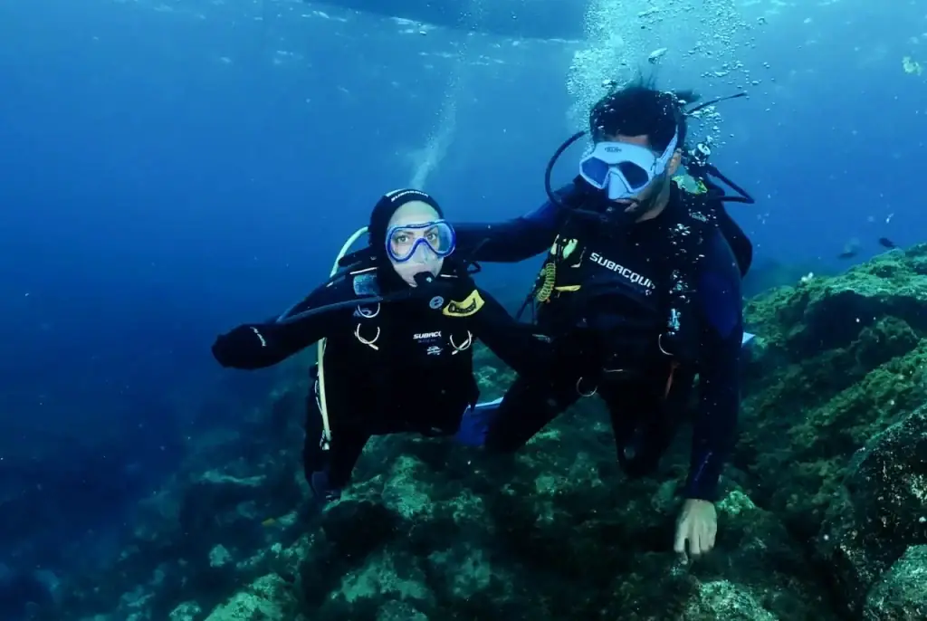 Dos buceadores posando bajo el agua durante una inmersión del campamento de buceo en Tenerife