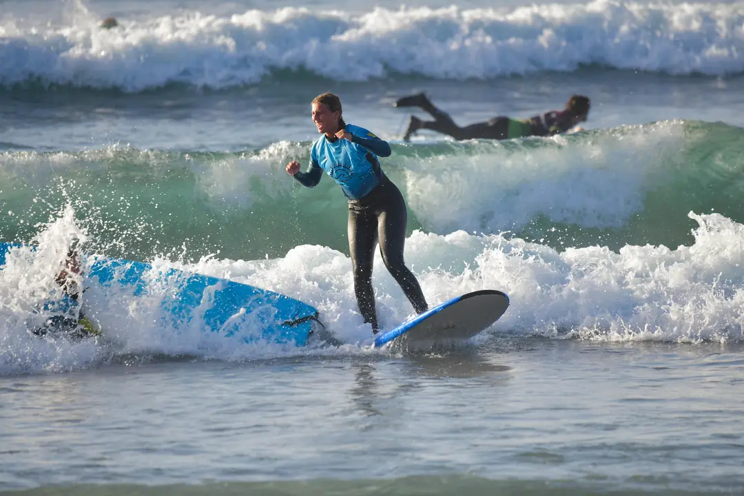 Clases de surf en Tenerife Alumna celebrando mientras surfea una ola en una clase de surf en Tenerife