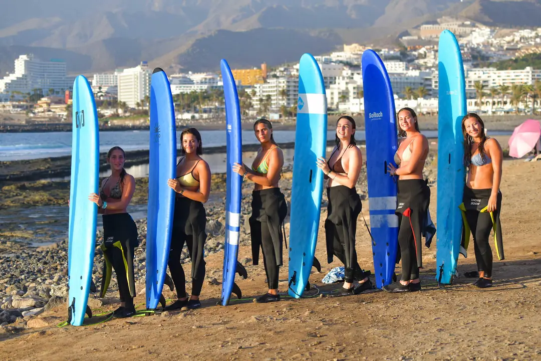 Alumnas de Single Fin posando con sus tablas de surf en Playa de Las Américas, Tenerife, con las montañas al fondo