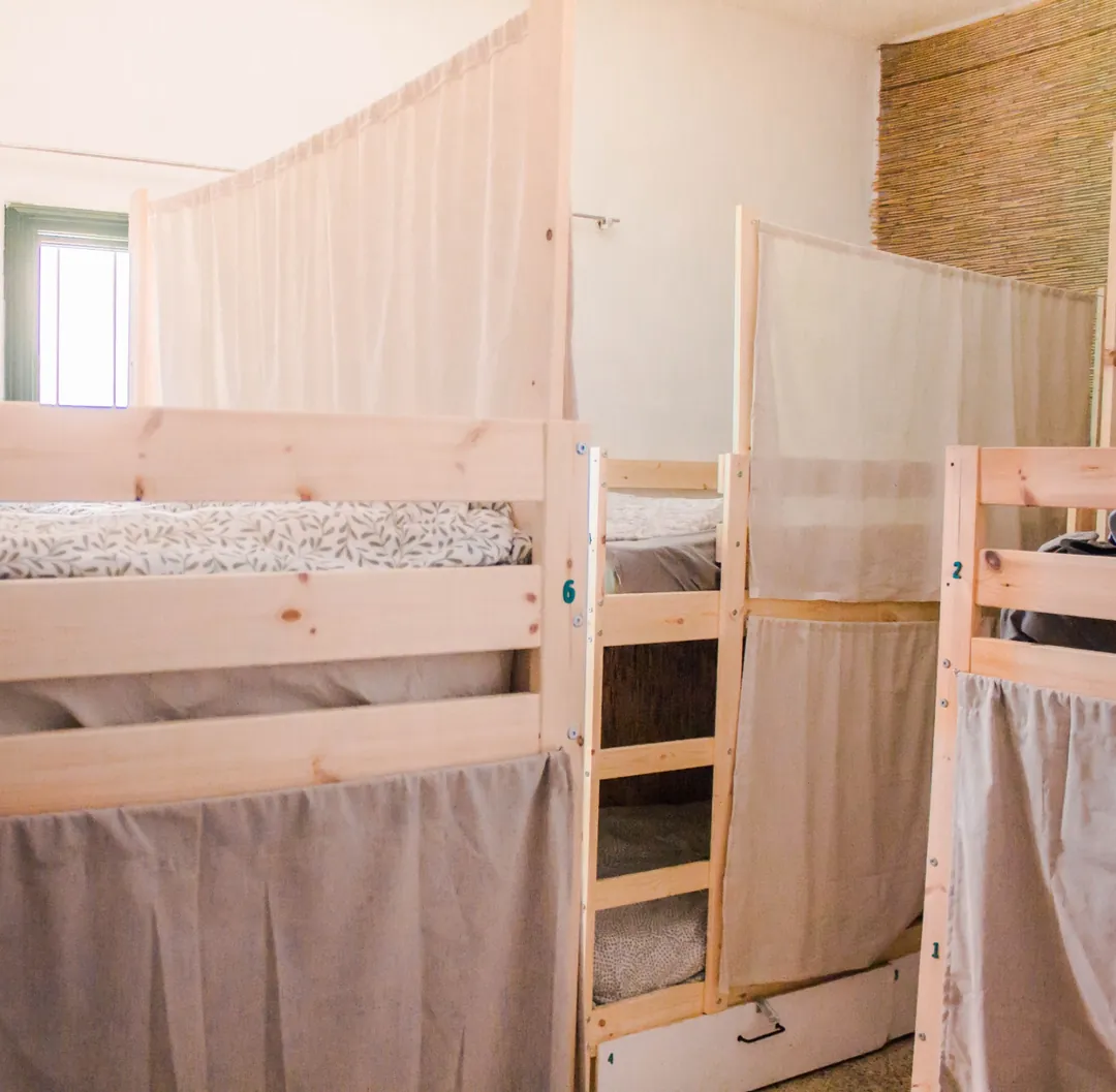 Habitación compartida de Single Fin Surf Hostel con literas de madera y cortinas para dar privacidad