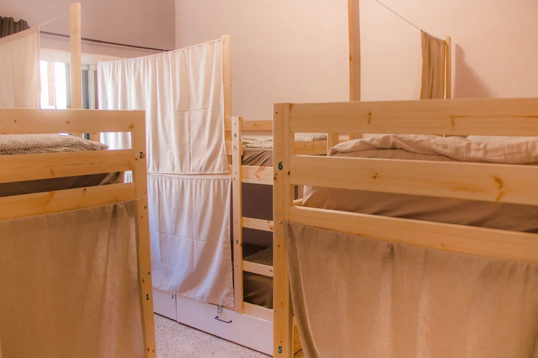 Literas de madera numeradas con cortinas en una habitación compartida de Single Fin Surf Hostel