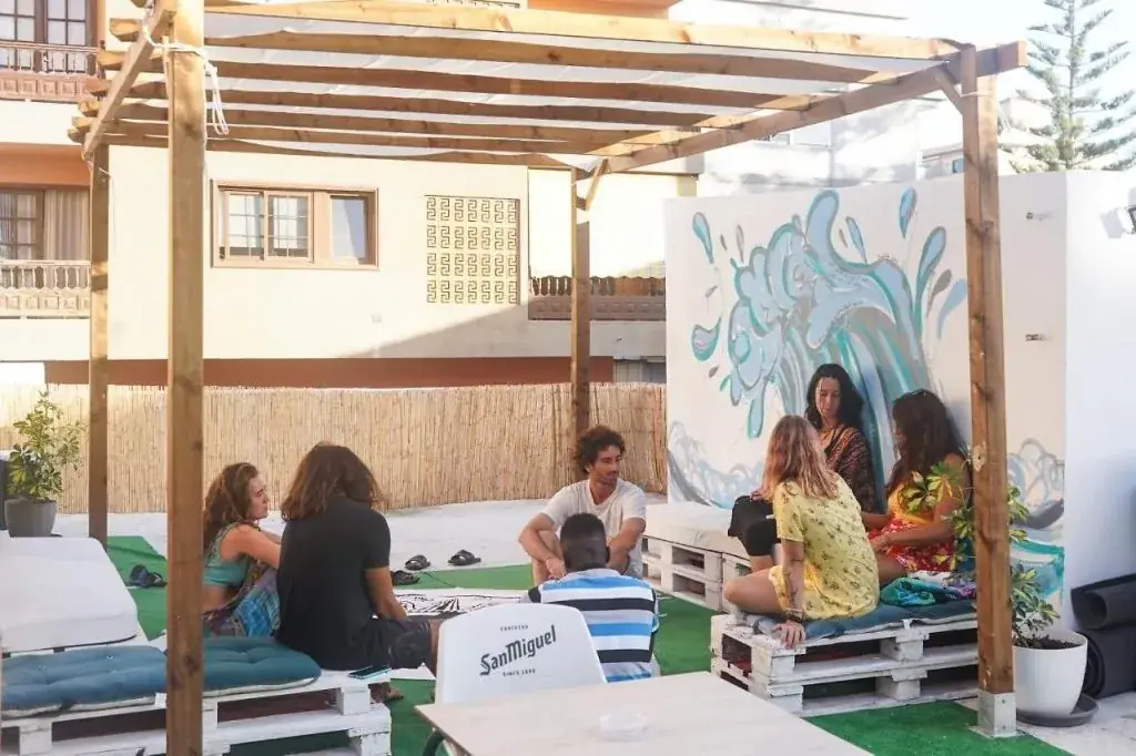 Huéspedes charlando bajo la pérgola de la terraza de Single Fin Surf Hostel