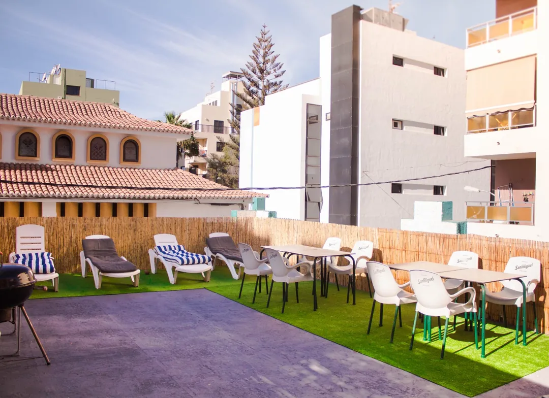 Terraza de Single Fin Surf Hostel con barbacoa, tumbonas y mesas para los huéspedes